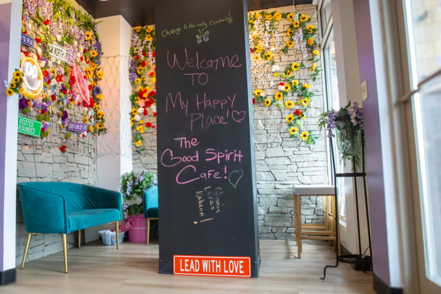 The café's welcome chalkboard framed by a wall of flowers
